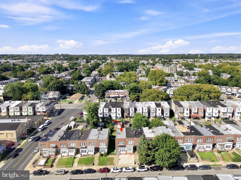 Aerial neighborhood view with a red arrow marking a rowhouse among tree-lined streets.
