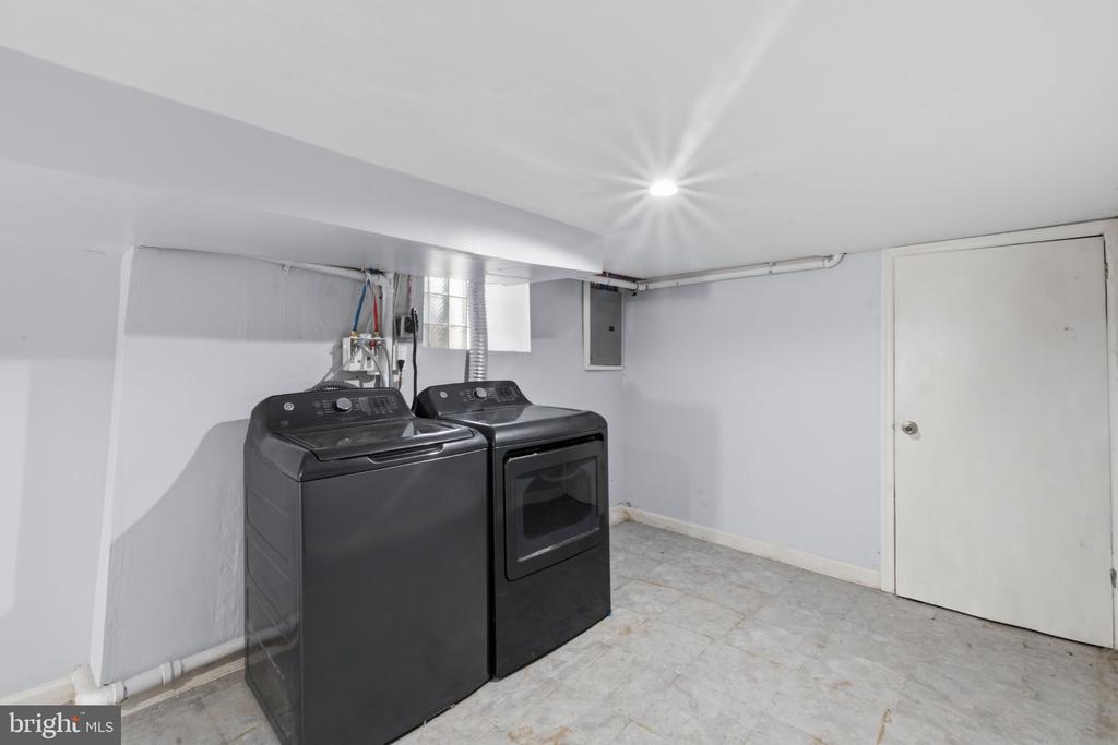 Basement laundry room with a black washer and dryer, glass-block window, and tiled floor.