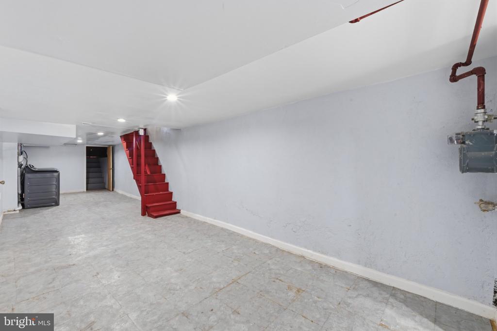 Unfinished basement with exposed utilities and a bright red staircase.