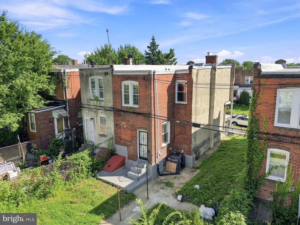 Rear of a brick rowhouse with a small patio and neighboring homes.