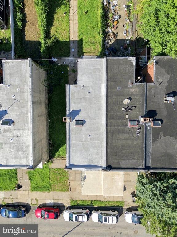 Aerial view of a rowhouse with a narrow rear yard, adjoining homes, and cars parked along the street.