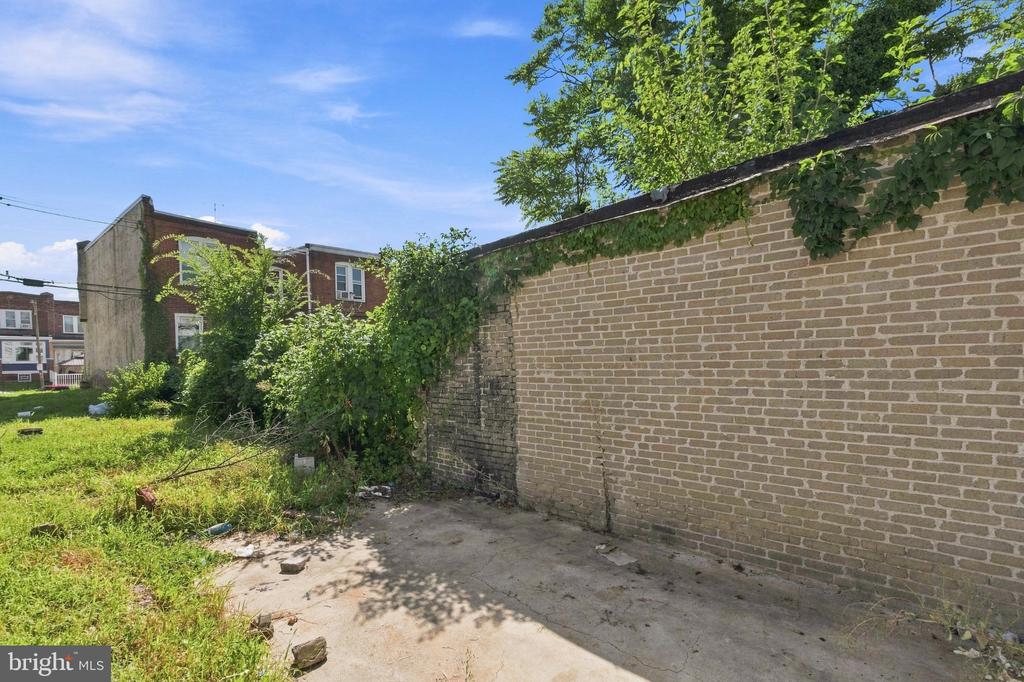 Concrete patio and grassy yard bordered by an ivy-covered brick wall.