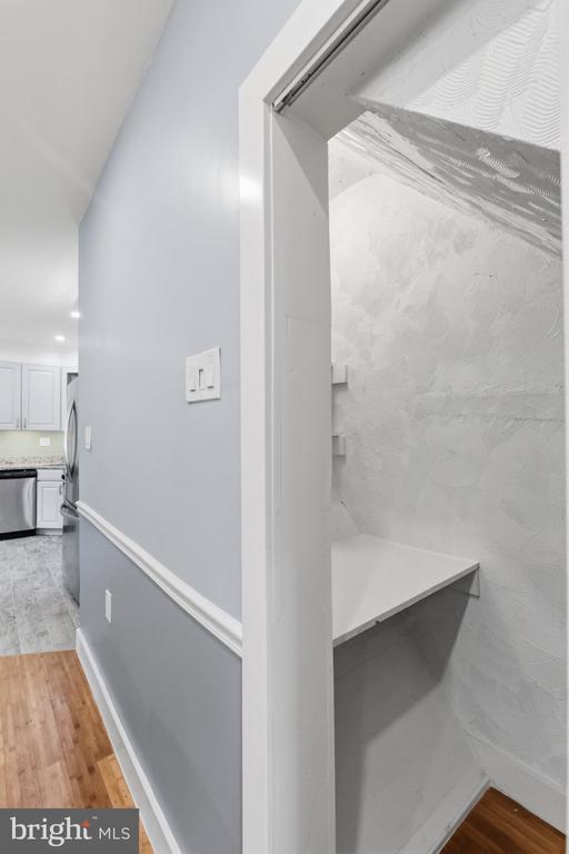 Tiled shower alcove with a built-in bench beside a narrow gray hallway.