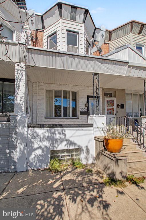 Attached home with a covered porch, upper bay windows, and an orange planter by the front steps.