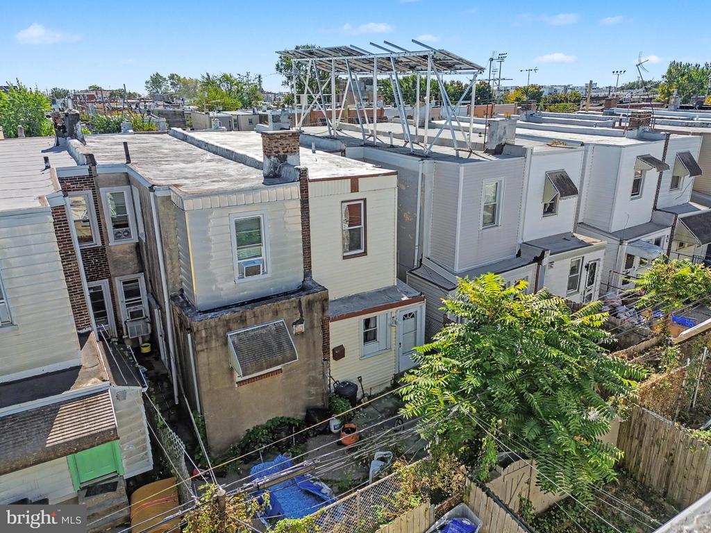 Aerial view of Philadelphia rowhouses with flat roofs, fenced yards, and a metal rooftop frame.
