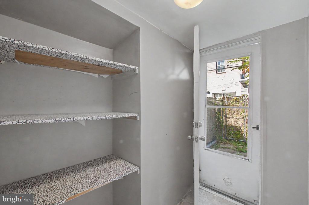 Storage room with patterned built-in shelves and a glass-paneled door to a fenced yard.