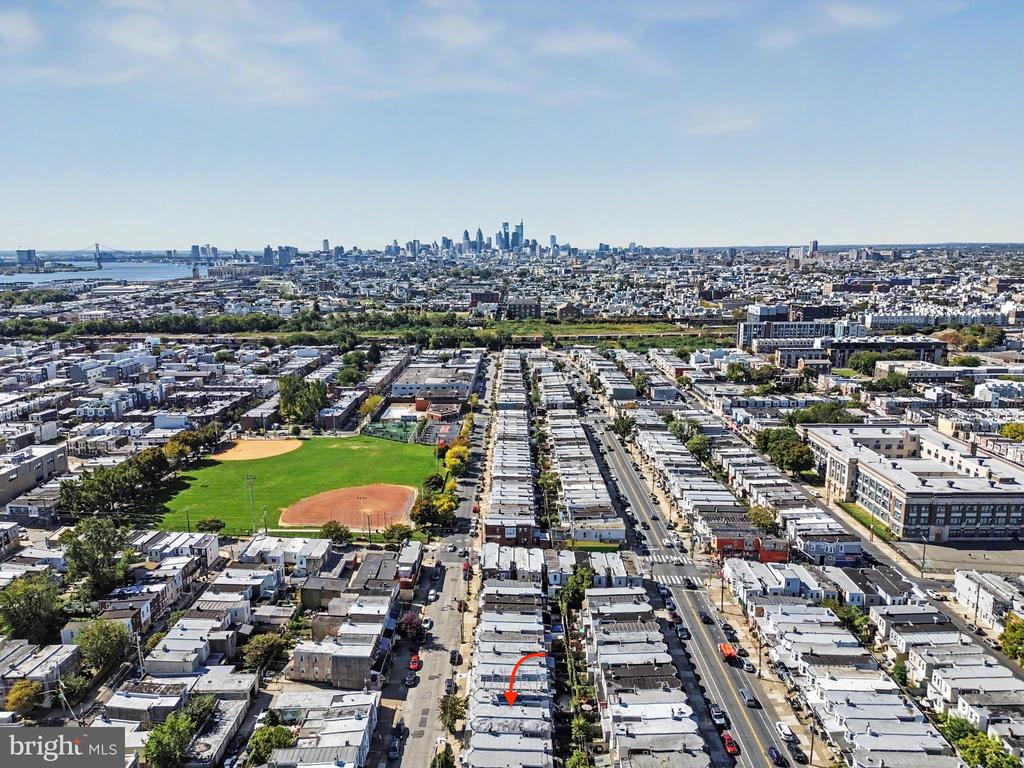 Aerial view of Philadelphia rowhouses, a baseball field, and the distant skyline.