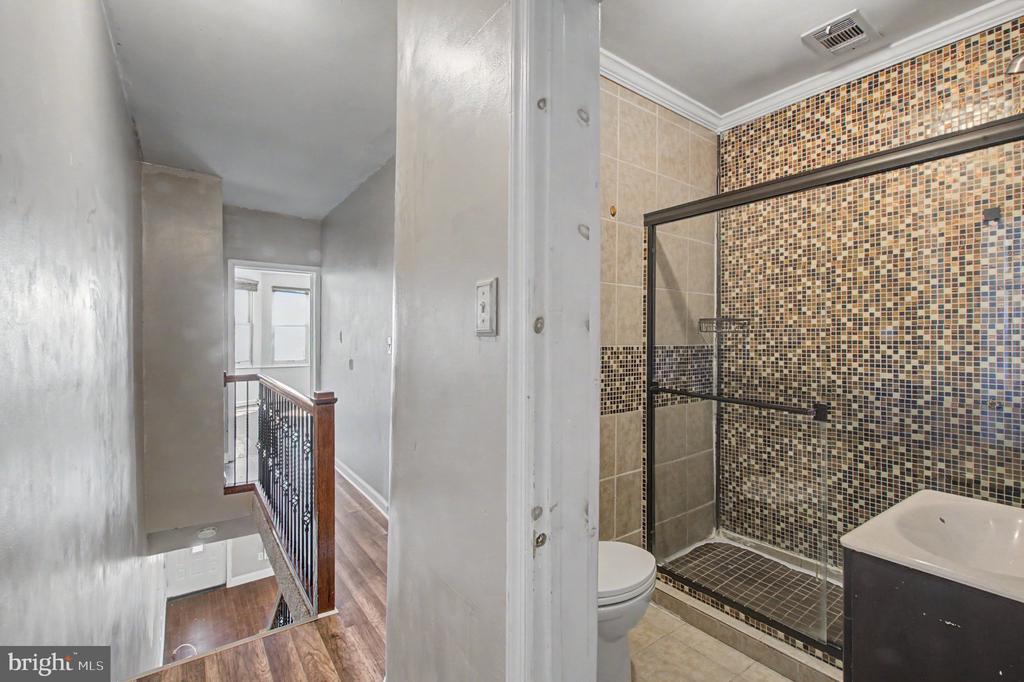 Bathroom with a mosaic-tile walk-in shower beside an upstairs hallway and stairwell.