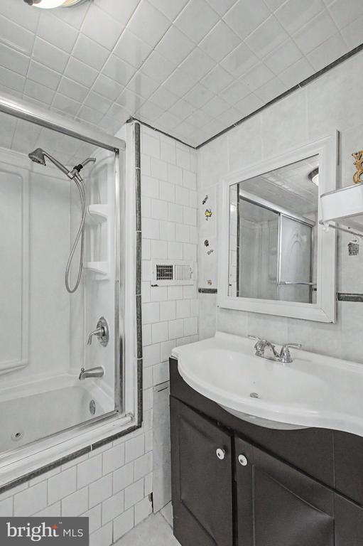 Bathroom with a glass-enclosed shower and dark vanity topped by a white sink.
