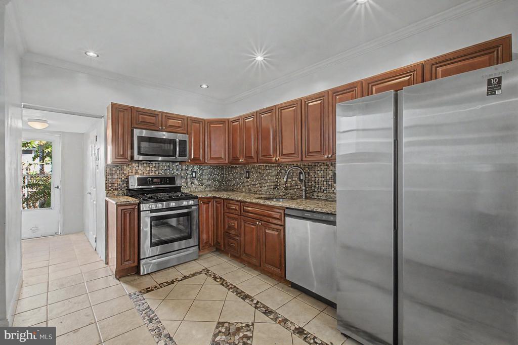 Kitchen with wood cabinets, stainless steel appliances, and a decorative tiled floor.