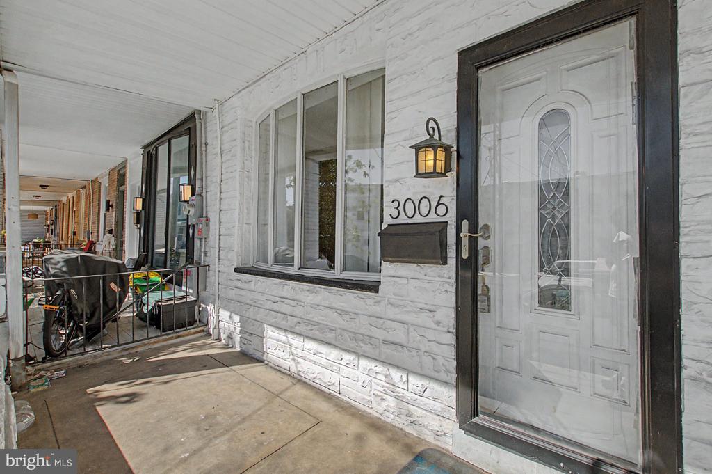 Covered front porch and entrance to a white stone-faced home marked 3006.