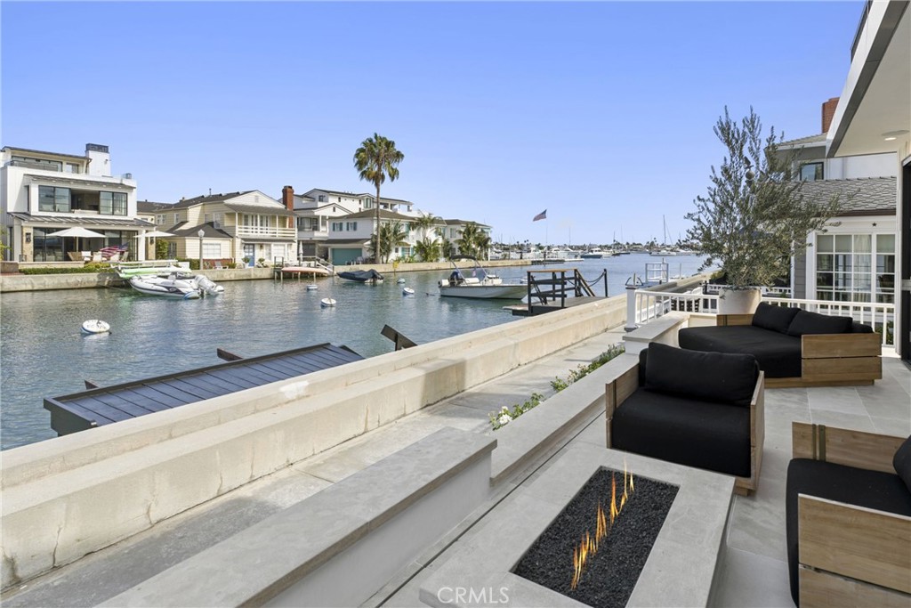 Waterfront patio with black lounge seating and a linear fire pit overlooking a Newport Beach canal.