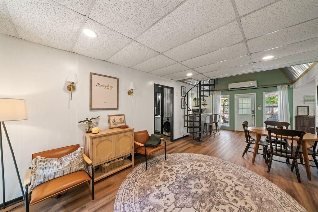 Open living and dining area with leather seating, a round rug, and a spiral staircase.