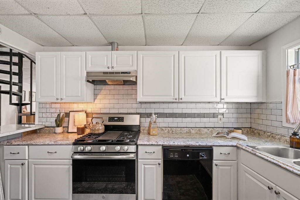 Kitchen with white cabinets, subway tile backsplash, granite counters, and a stainless steel range.
