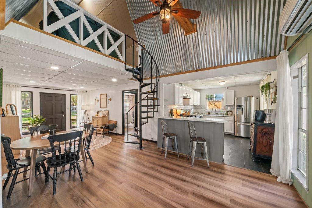 Open-plan kitchen and dining area with a spiral staircase and vaulted metal ceiling.