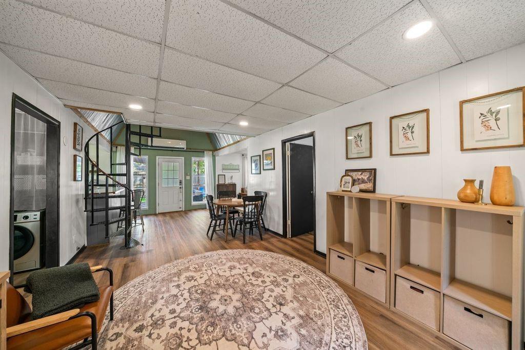 Furnished open room with a dining table, spiral staircase, and built-in shelving.
