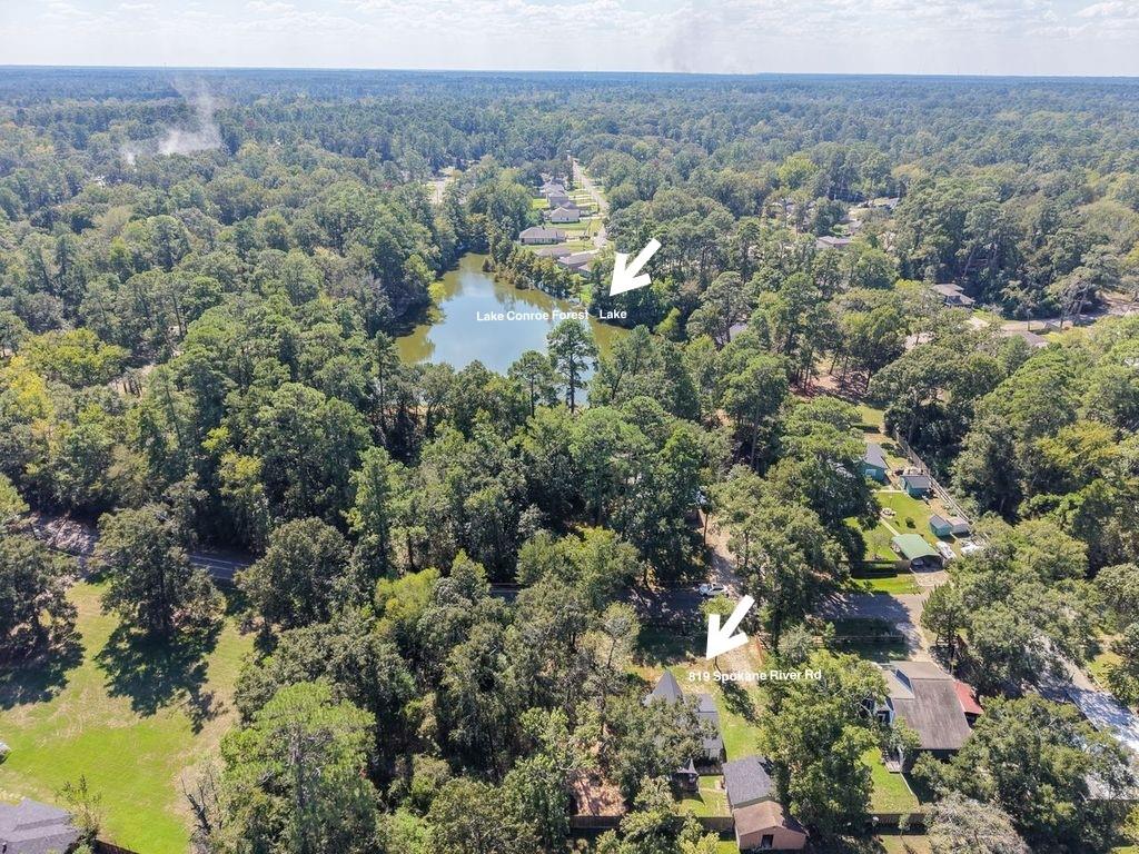 Aerial view of wooded neighborhood and lake, with arrows marking the property and lake.