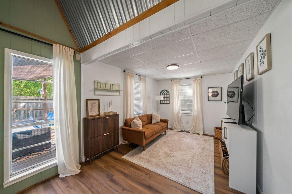 Living room with a brown sofa, light area rug, and vaulted metal ceiling.
