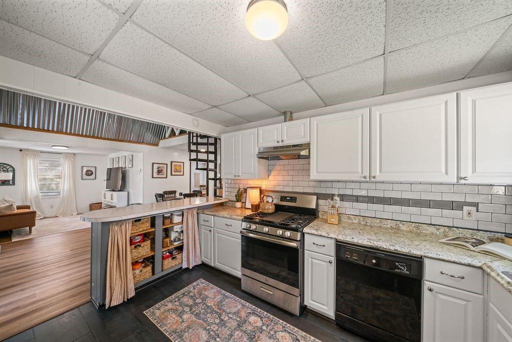 Kitchen with white cabinets, subway tile backsplash, and a black range.