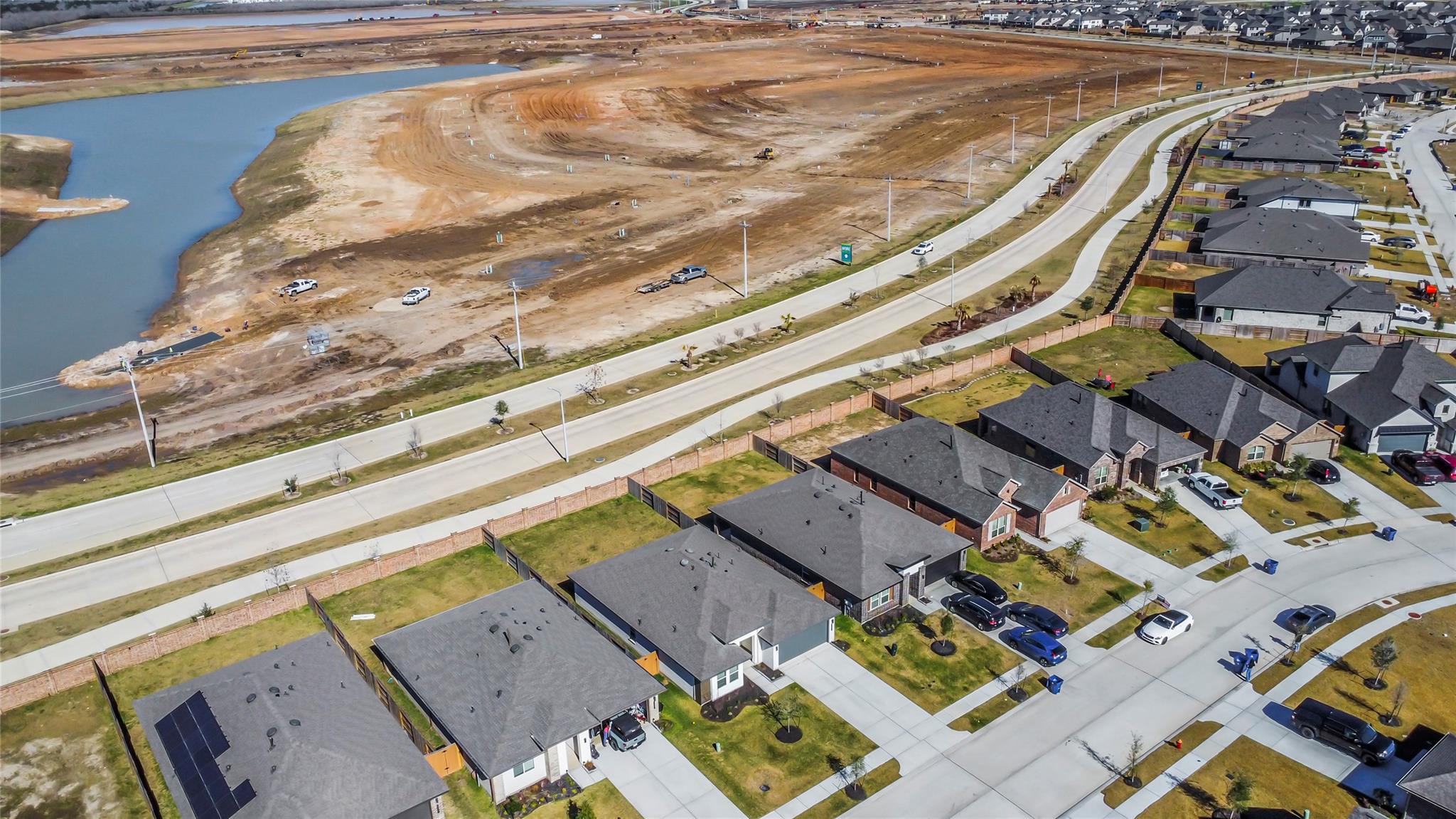 Aerial view of homes bordering a cleared construction site and winding waterway.