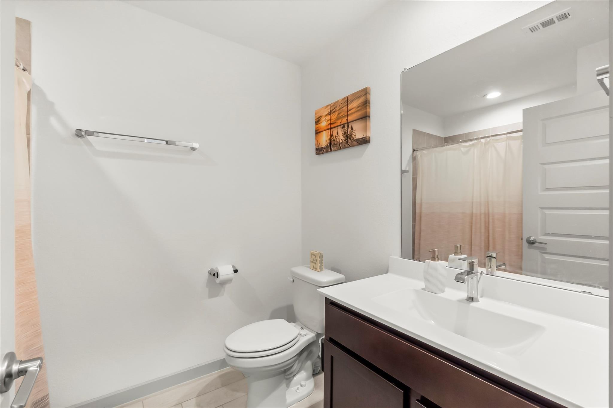 Bathroom with a dark wood vanity, large mirror, and peach-toned shower curtain.