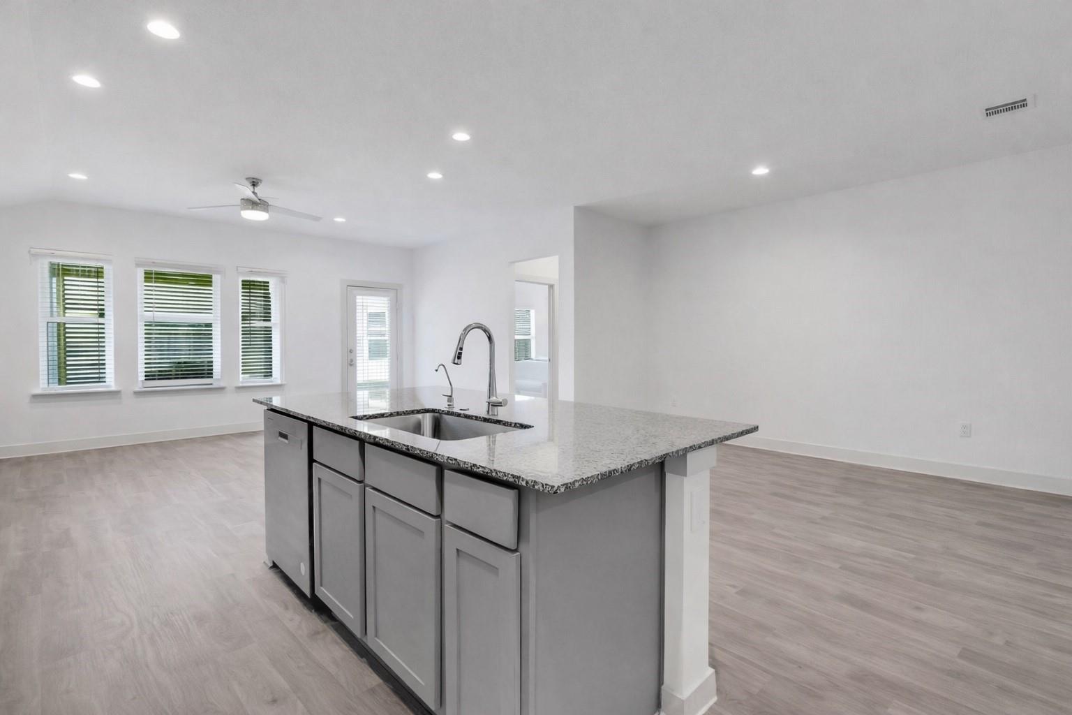 Open-plan kitchen with a large gray island, speckled stone countertop, and built-in sink.