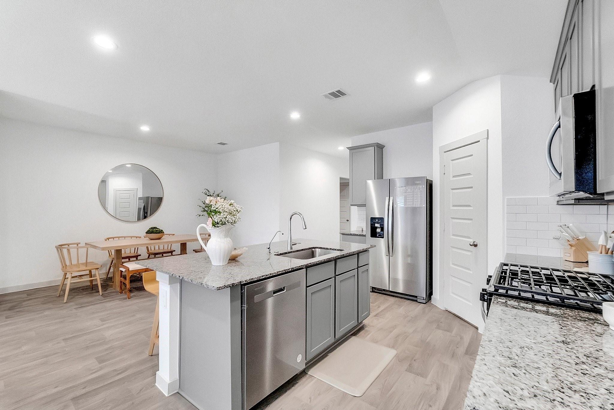 Modern kitchen with a granite island, stainless steel appliances, and an adjoining dining area.