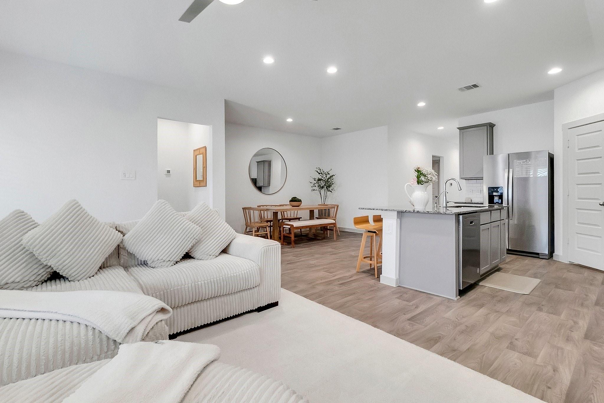 Open-plan living room with a white sectional, wood dining set, and gray kitchen island.