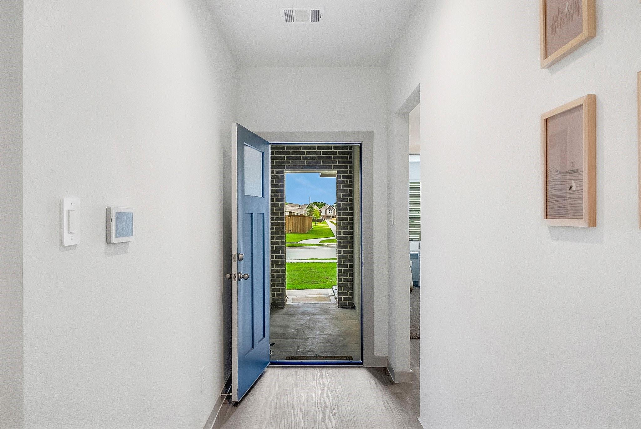 Entry hall with an open blue front door overlooking the lawn and neighboring homes.