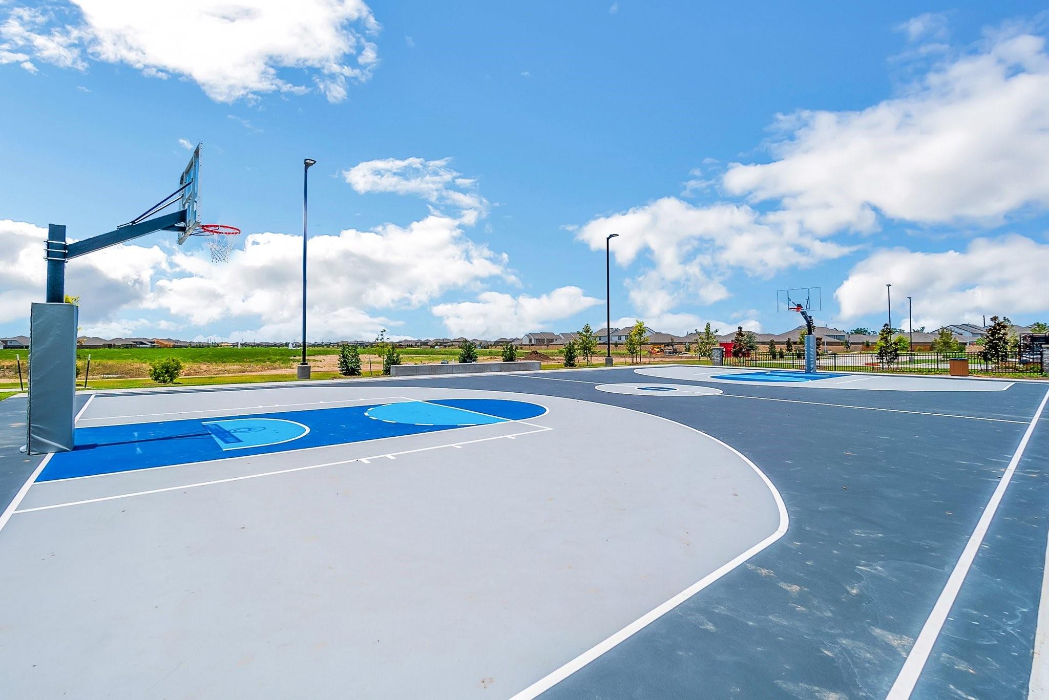 Outdoor basketball court with blue and gray surfaces and multiple hoops.