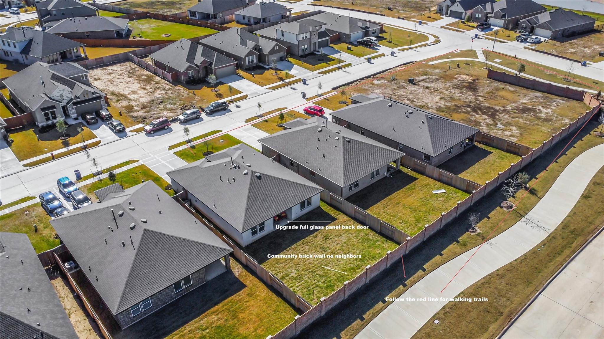 Aerial view of a home’s fenced backyard, with a brick wall and walking trail route marked in red.