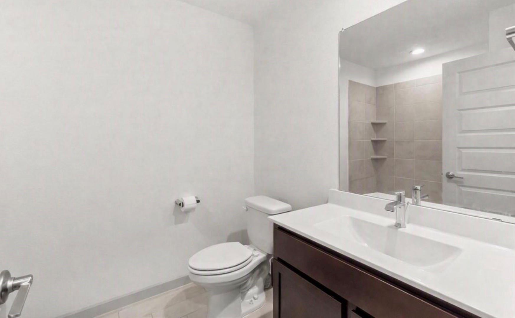 Bathroom with a dark wood vanity, white countertop, and mirrored view of a tiled shower.