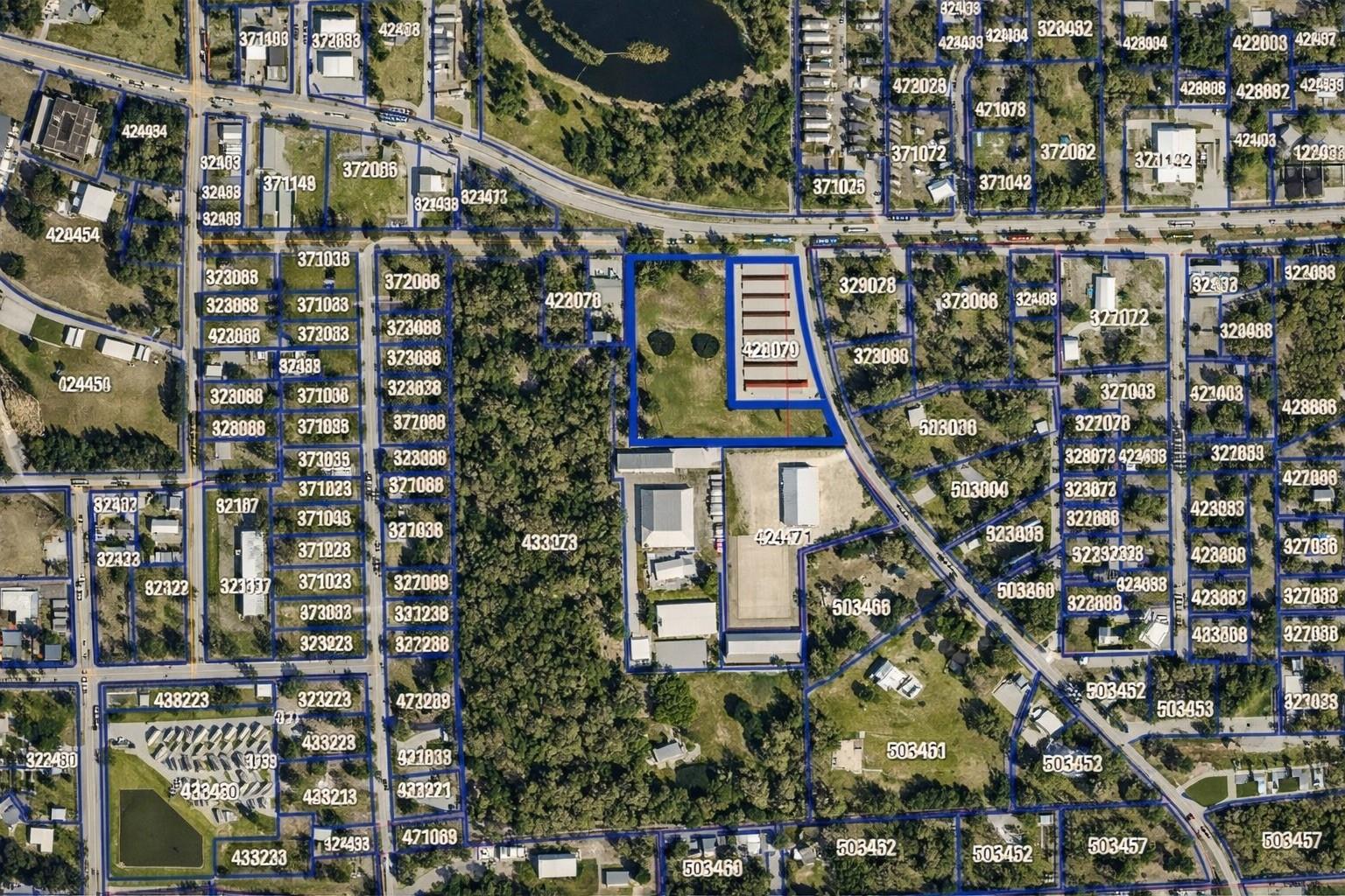 Aerial parcel map with blue lot boundaries and numbered properties, highlighting a larger central parcel.