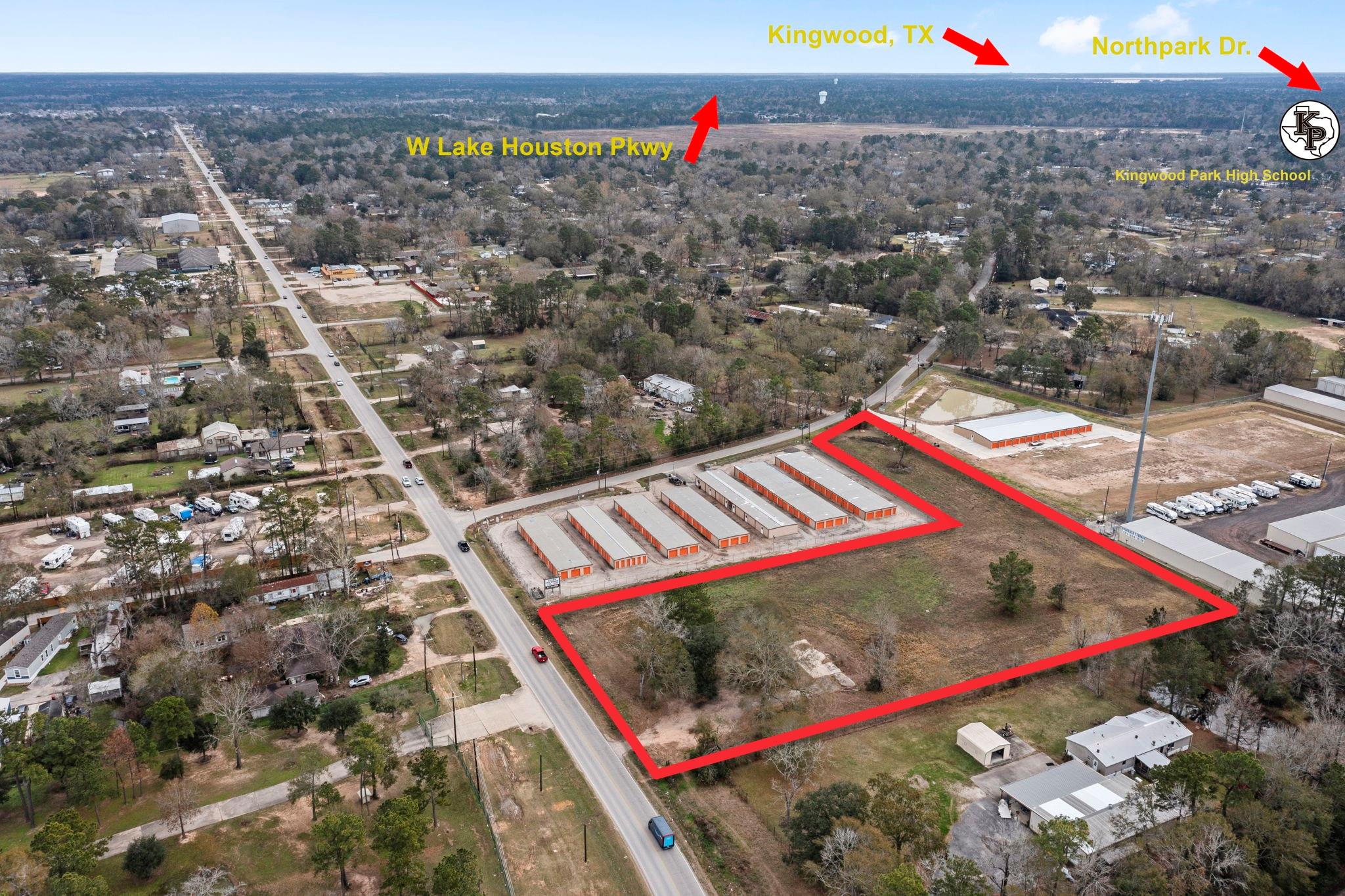 Aerial view of vacant land outlined in red beside storage buildings and a road.