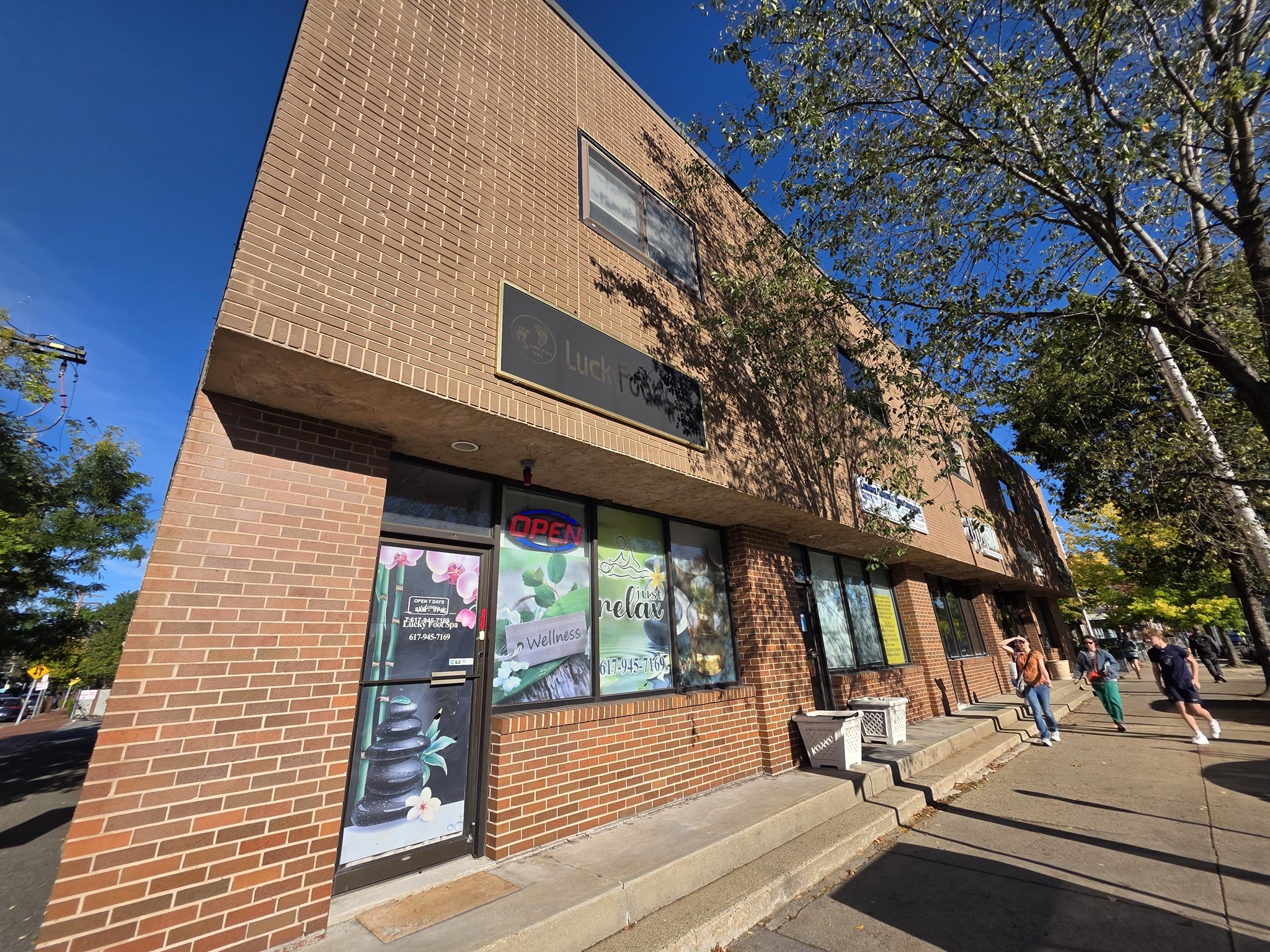 Brick commercial building with a spa storefront and pedestrians on the sidewalk.