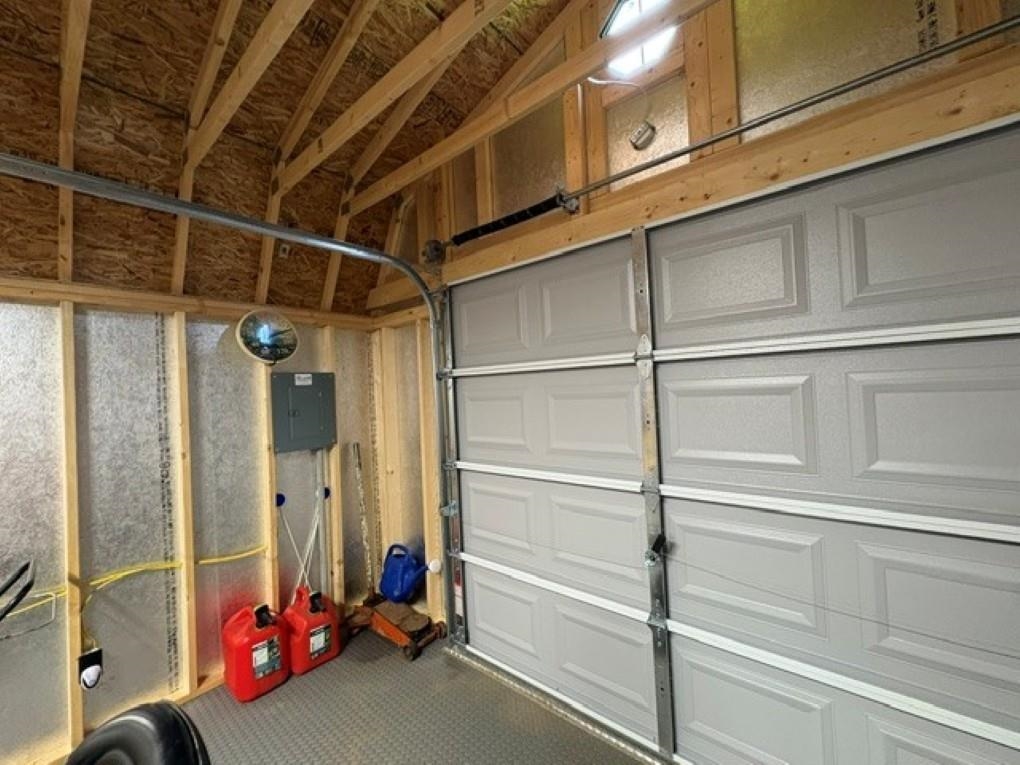 Garage interior with a sectional overhead door and exposed wooden roof framing.