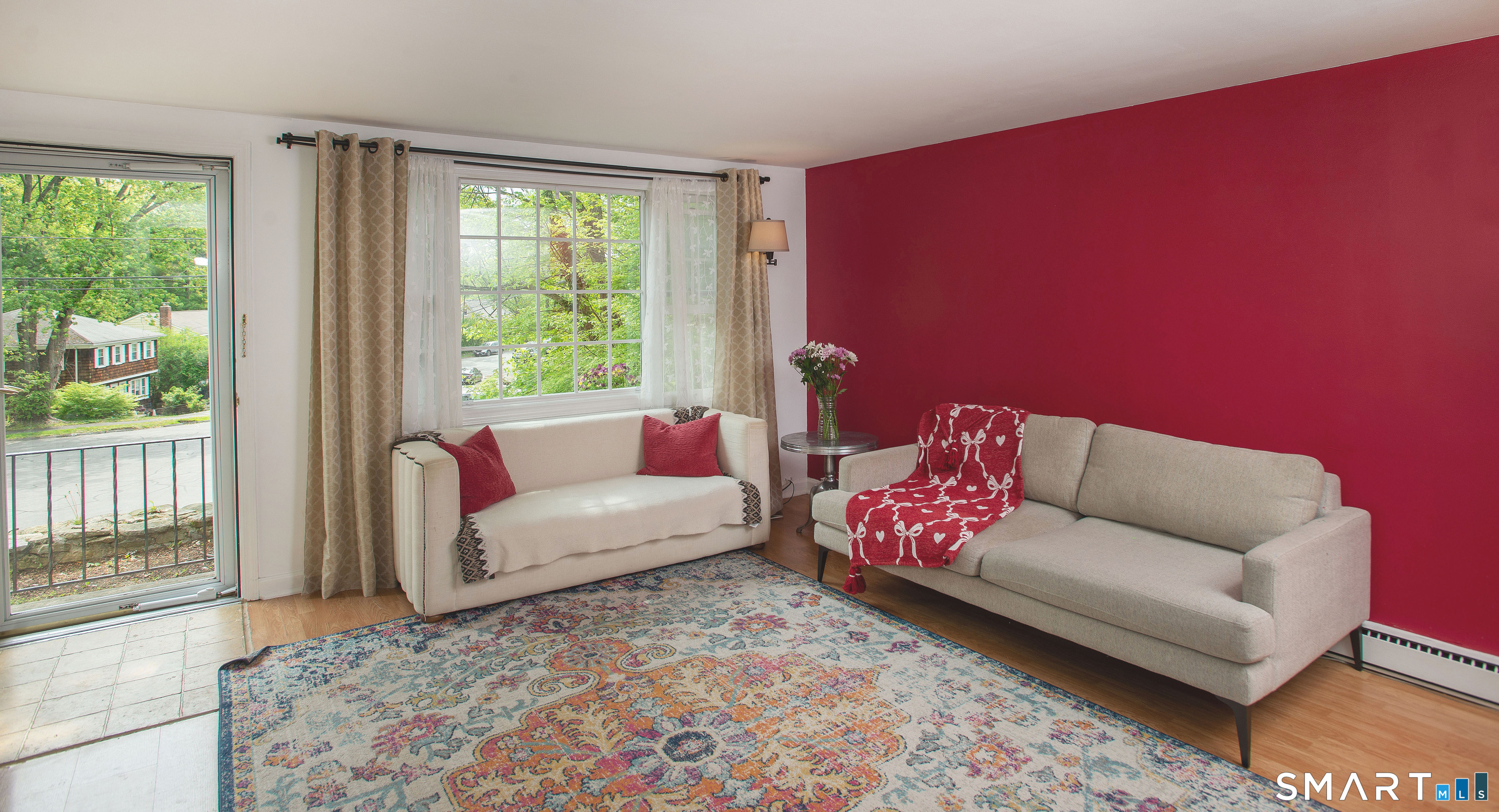 Living room with cream sofas, a colorful patterned rug, and a burgundy accent wall.