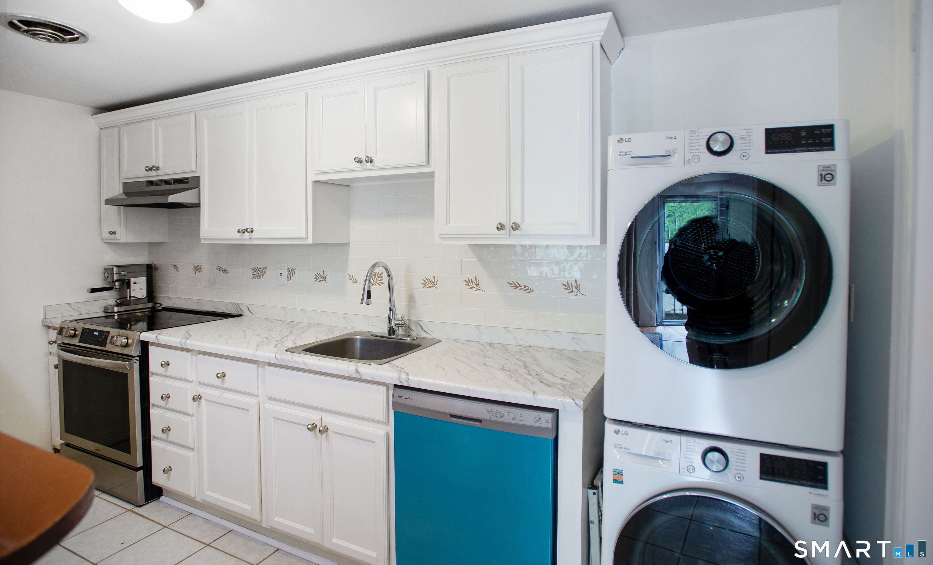 Kitchen with white cabinetry, a turquoise-front dishwasher, and stacked washer and dryer.