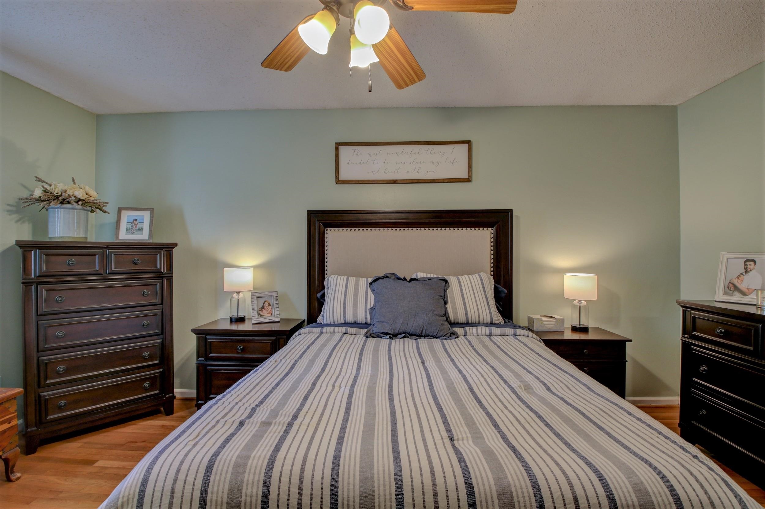 Furnished bedroom with striped bedding, dark wood furniture, and matching bedside lamps.