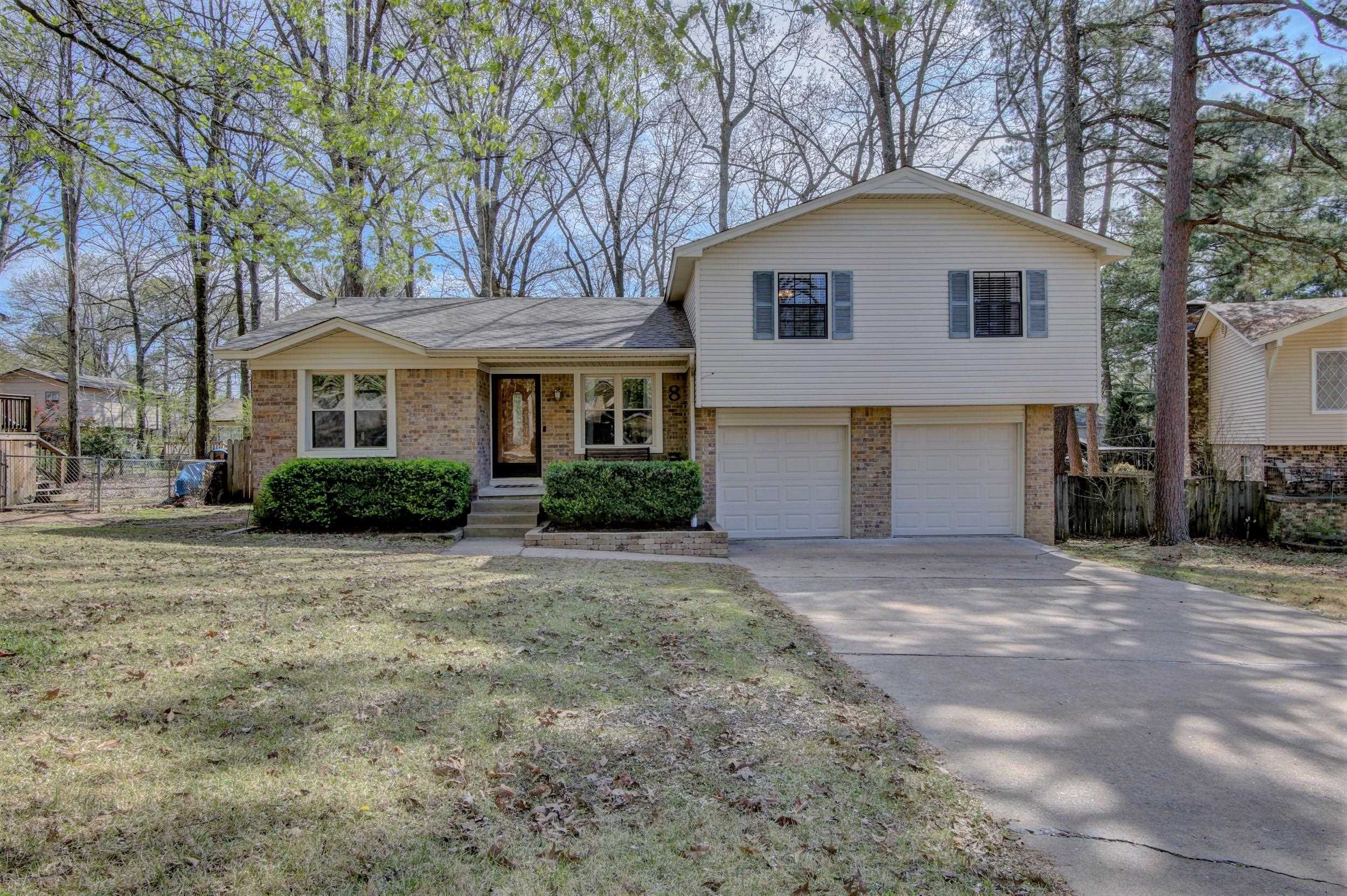 Split-level home with brick and light siding, blue shutters, and a two-car garage.