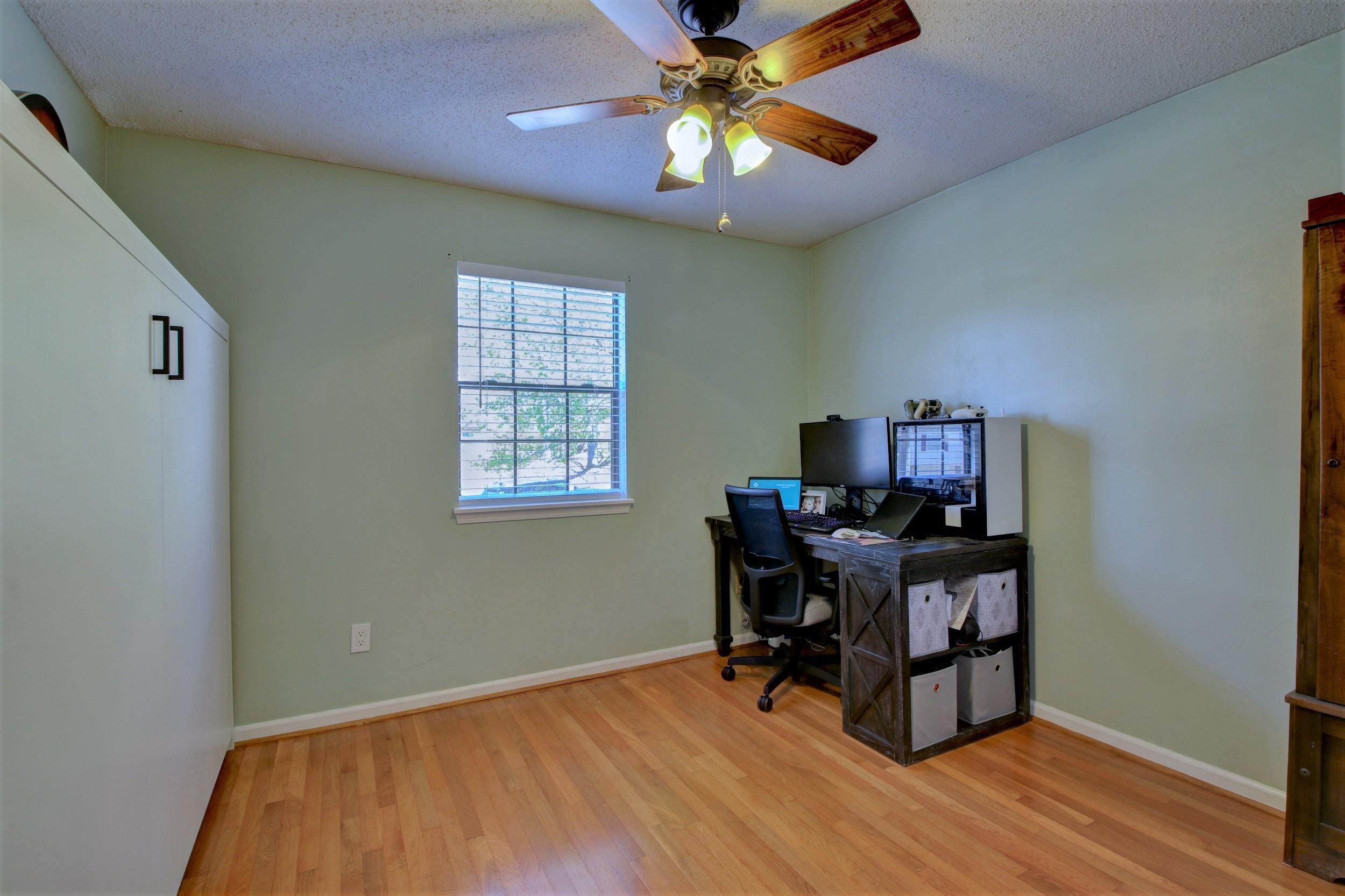 Home office with hardwood floors, a window with blinds, and a computer workstation.
