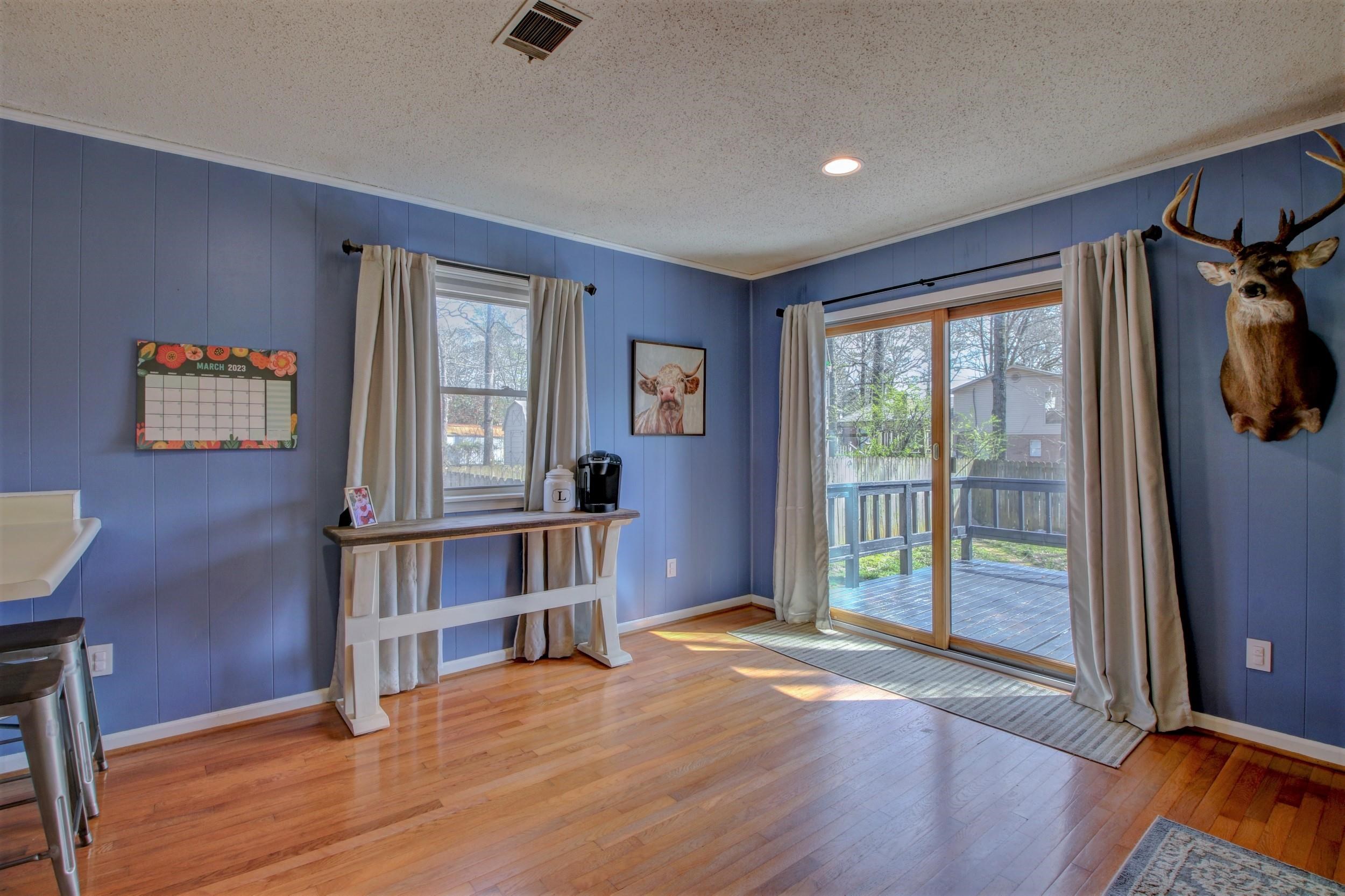 Blue-walled room with hardwood floors and sliding glass doors opening onto a deck.