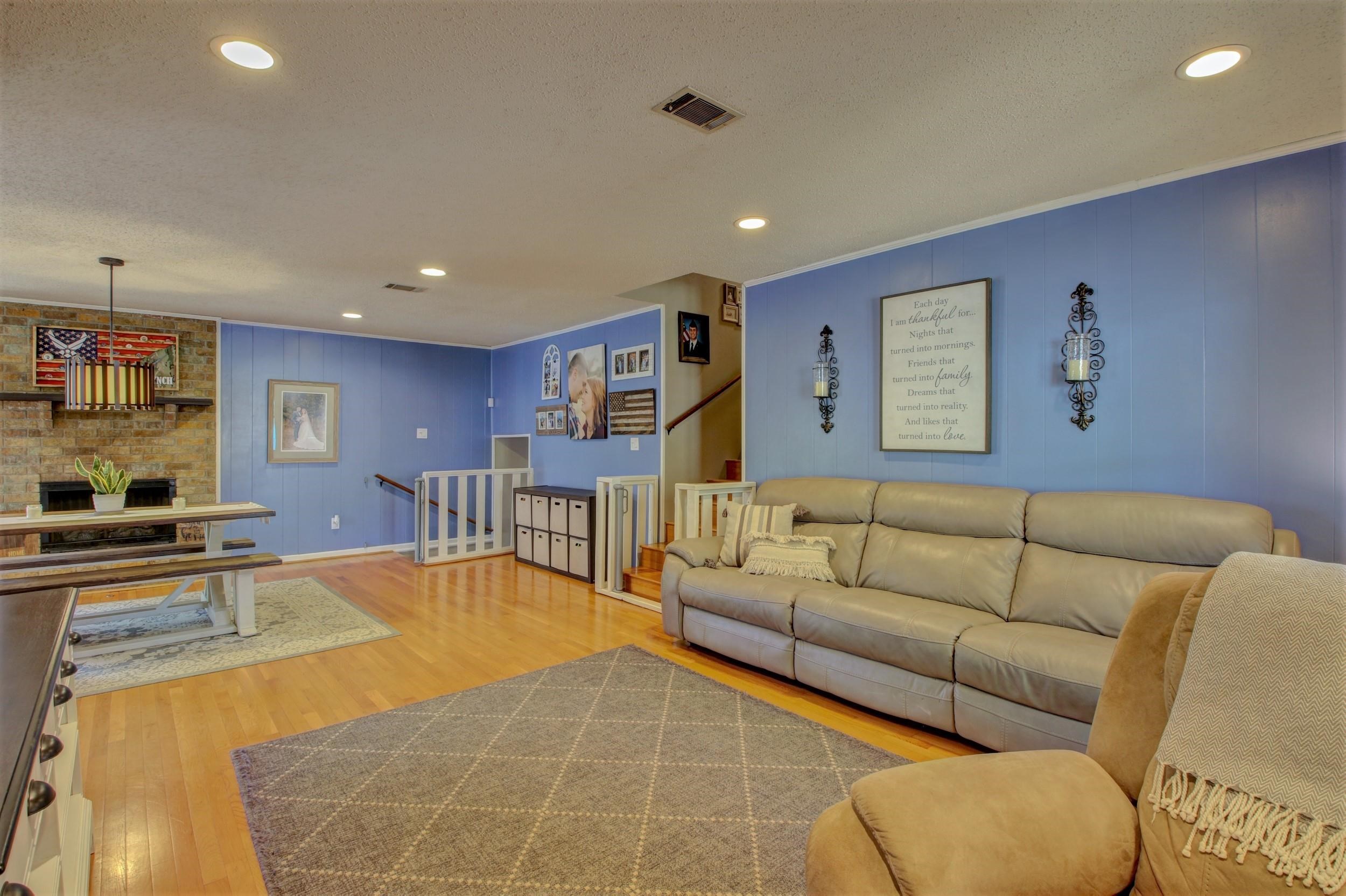 Living room with blue paneled walls, a beige sectional sofa, and a brick fireplace.