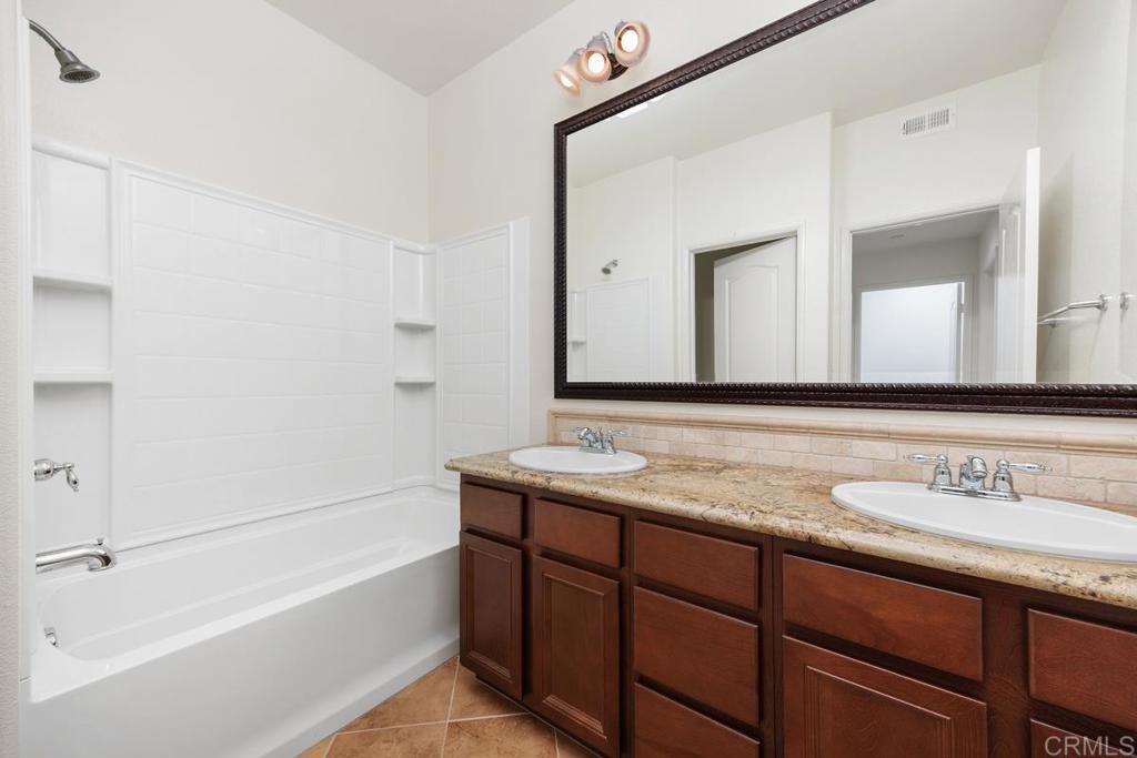 Bathroom with a white tub, built-in shower niches, and a dark wood double vanity.