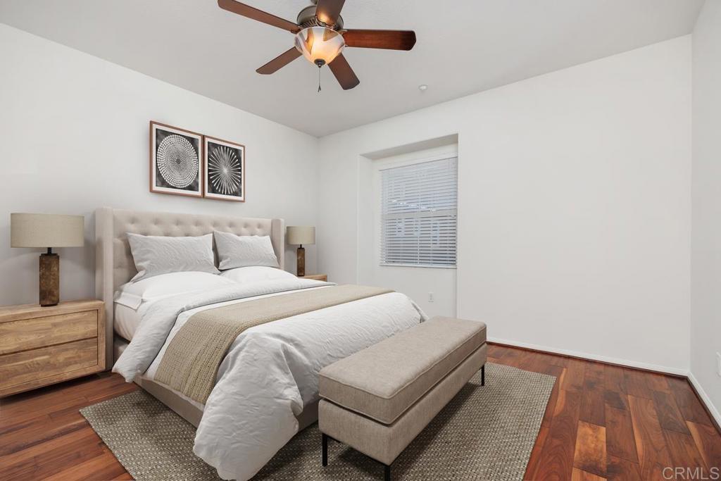 Staged bedroom with a tufted bed, beige bench, geometric wall art, and hardwood floors.