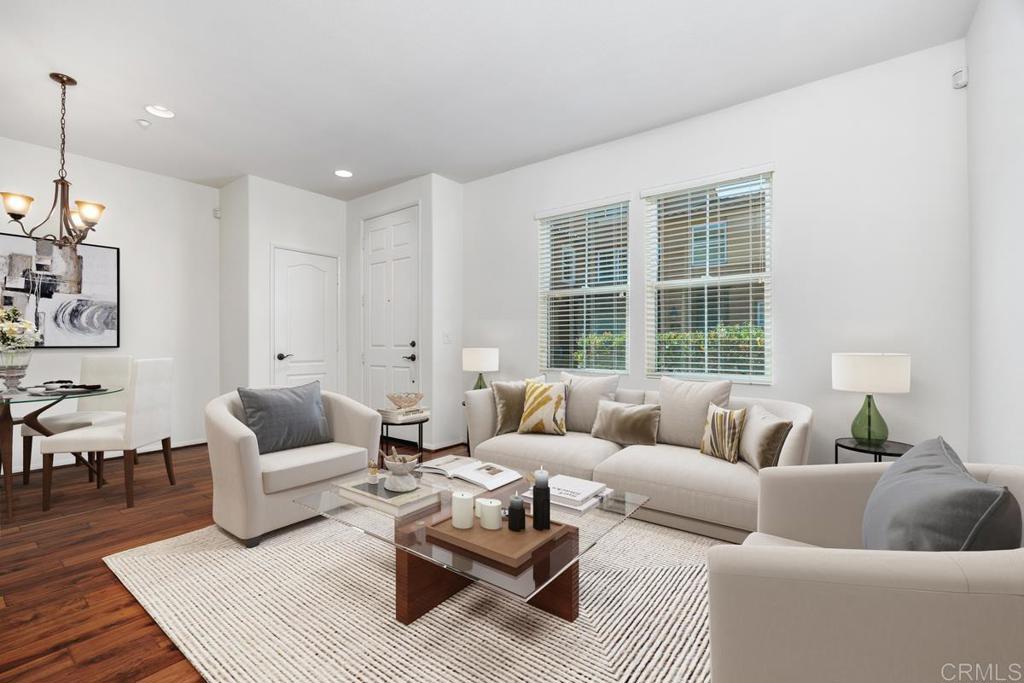 Living room with a cream sectional, glass coffee table, and windows with blinds.