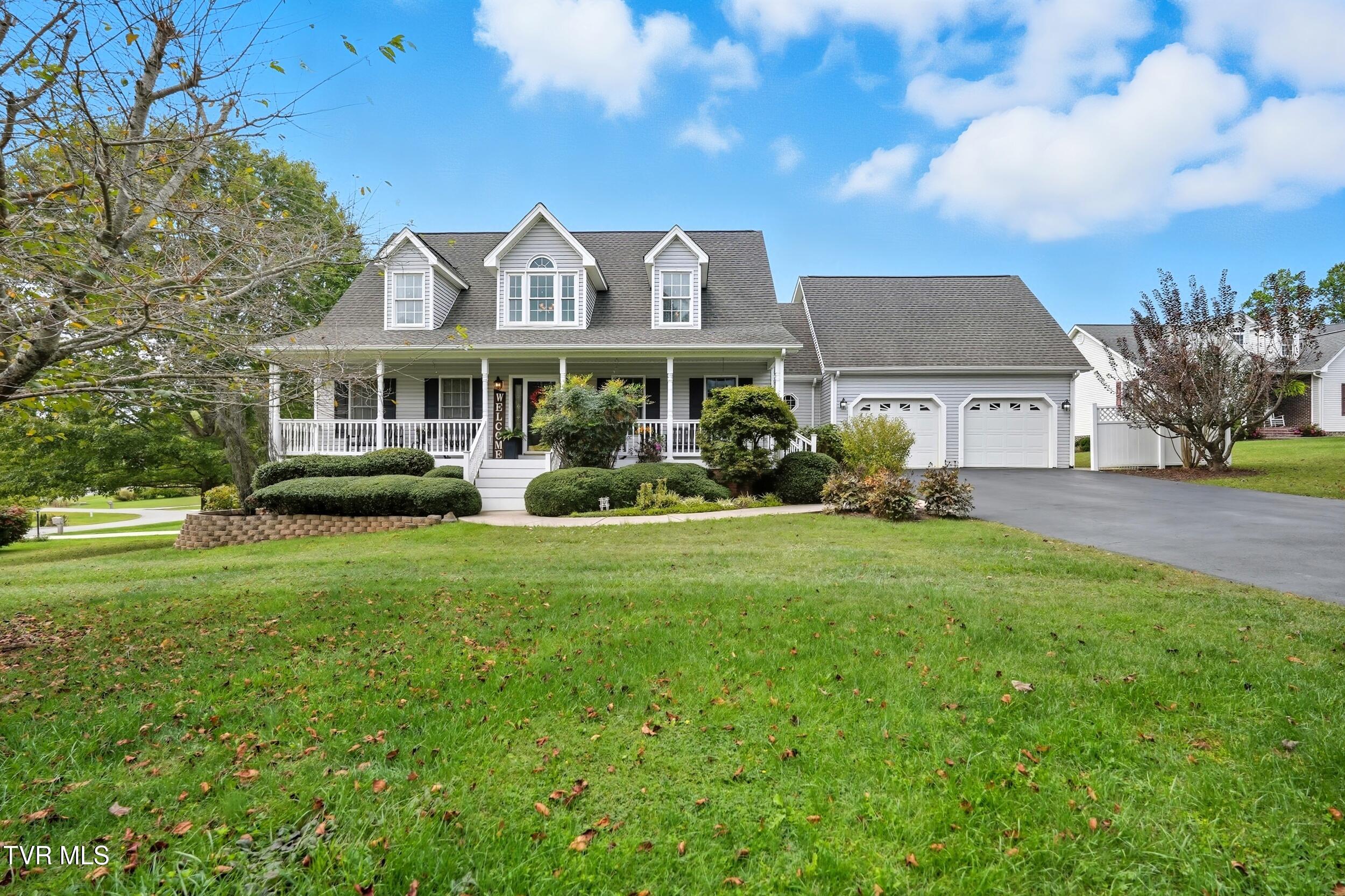 Gray two-story home with a covered porch, three dormers, and an attached two-car garage.