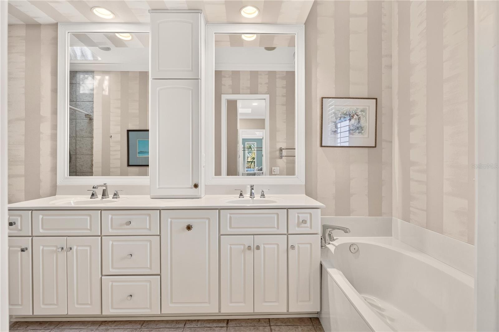 Bathroom with a white double vanity, framed mirrors, and a built-in bathtub.