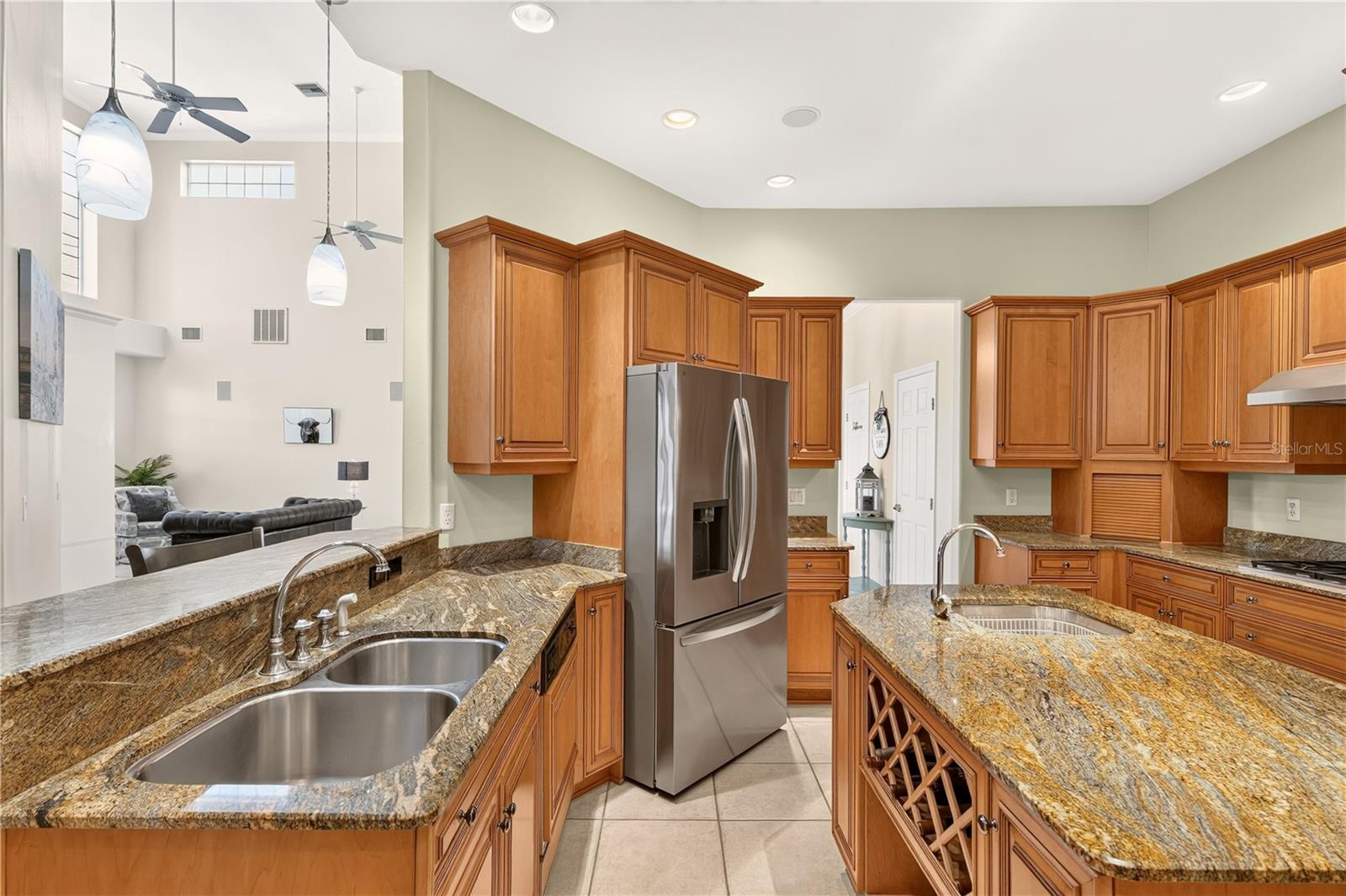 Kitchen with wood cabinets, granite counters, stainless refrigerator, and a central island.