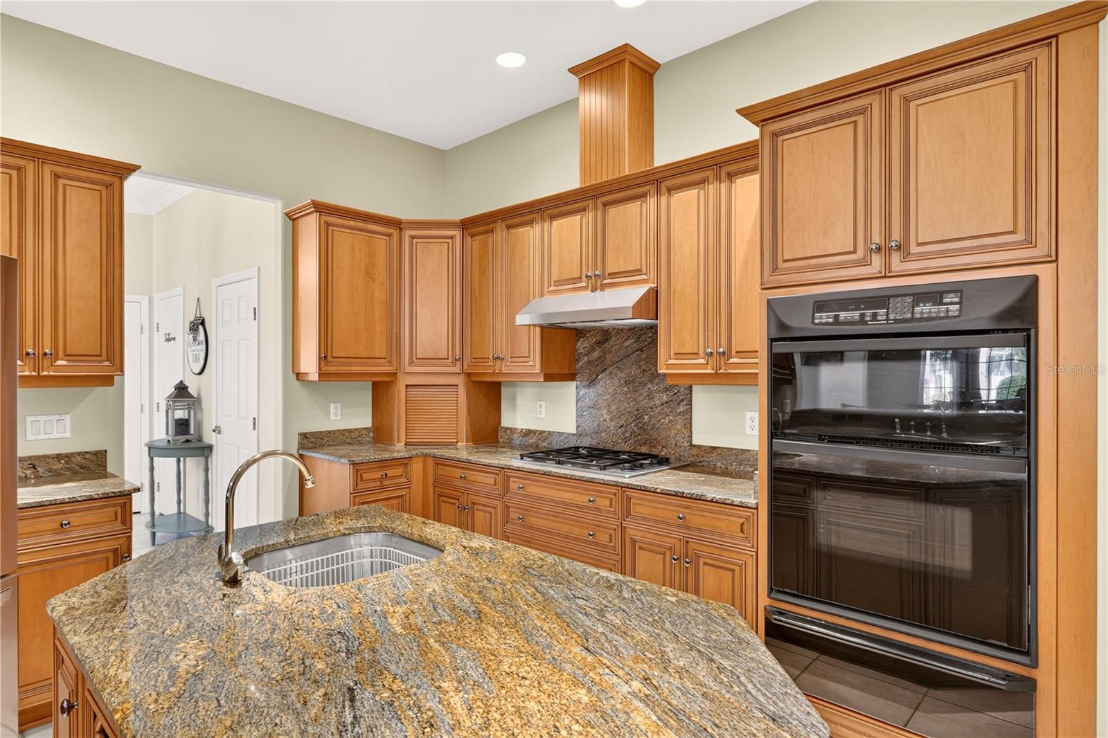 Kitchen with wood cabinets, granite island, gas cooktop, and double wall oven.